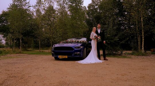Videograaf Nunspeet - Trouwfilm met bruidspaar bij trouwauto.